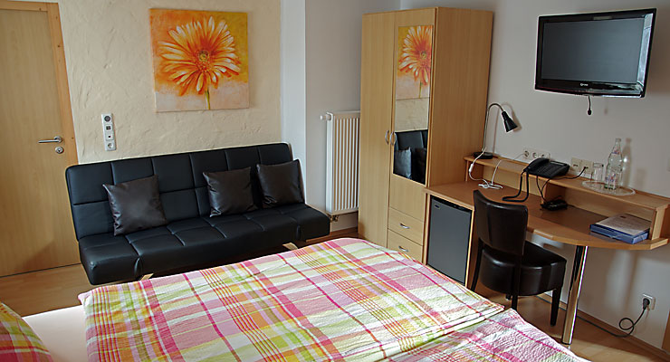 Gästezimmer mit Couch und Schreibtisch im Gästehaus Kloep in Hillesheim
